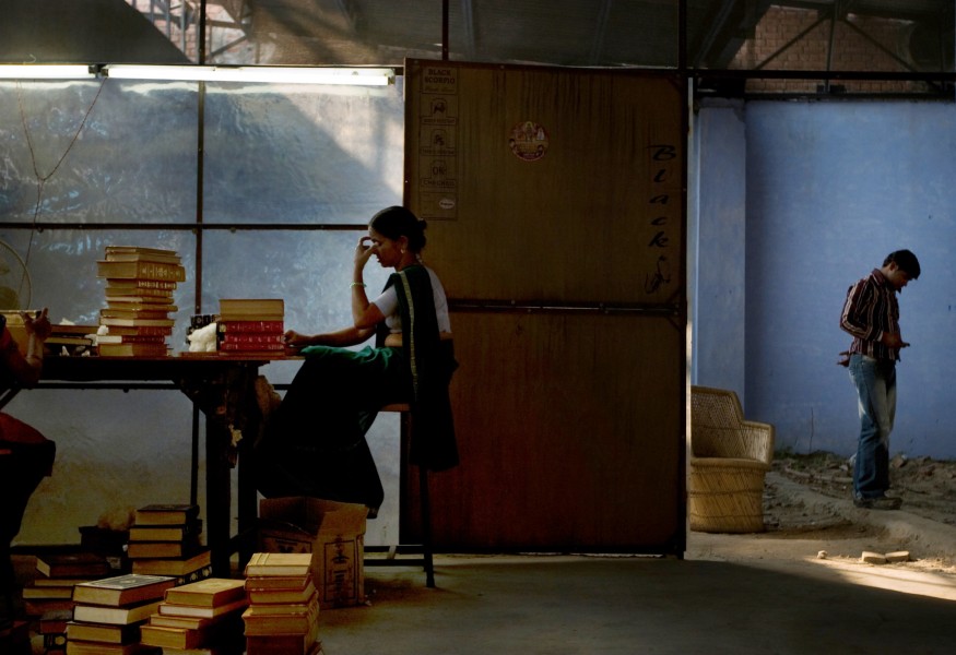 Gudi Davi takes a momentary break from her work binding books in a factory in New Delhi, India